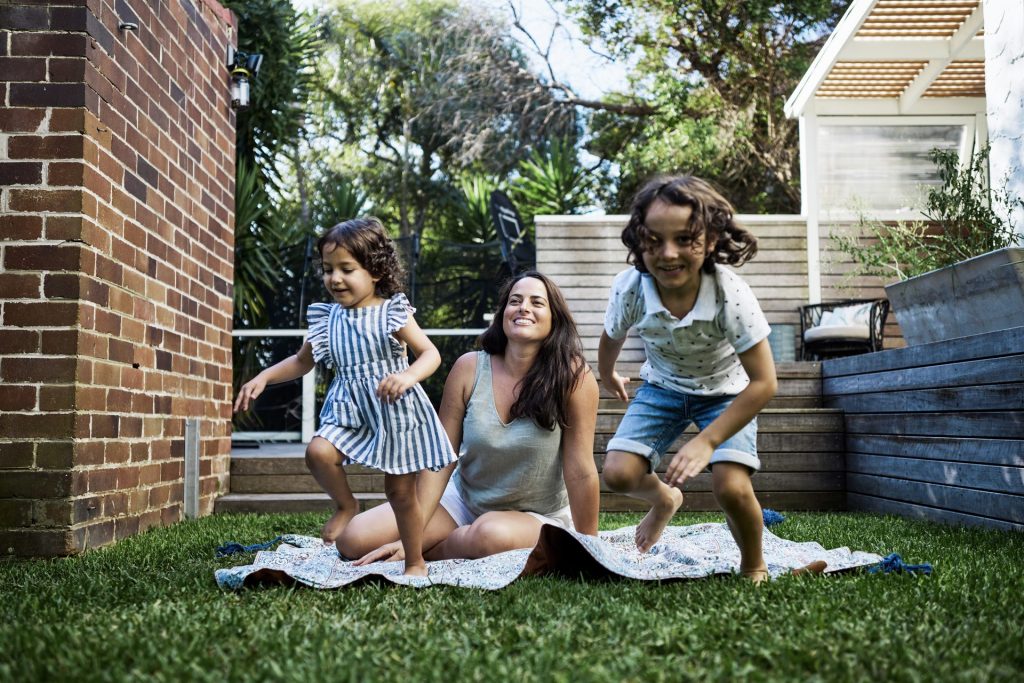 Mother and children playing on backyard lawn