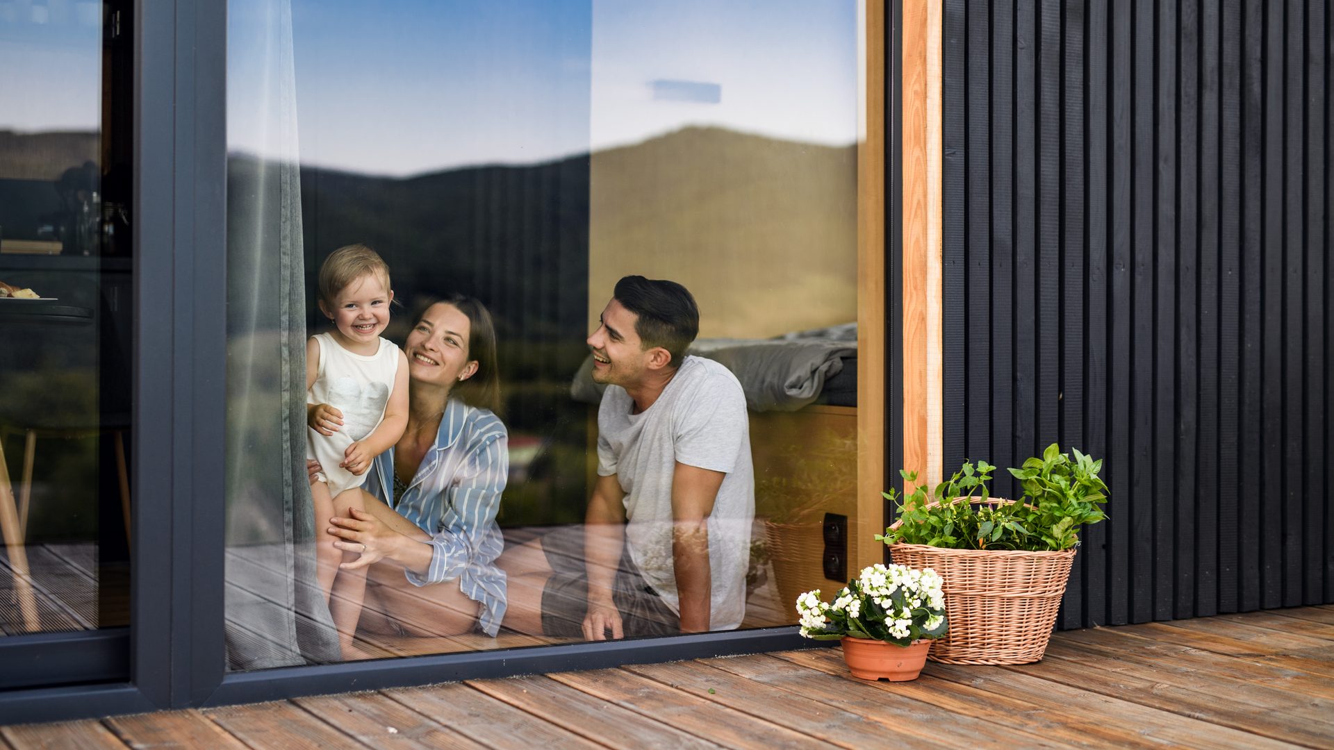Family smiling through cabin window in countryside