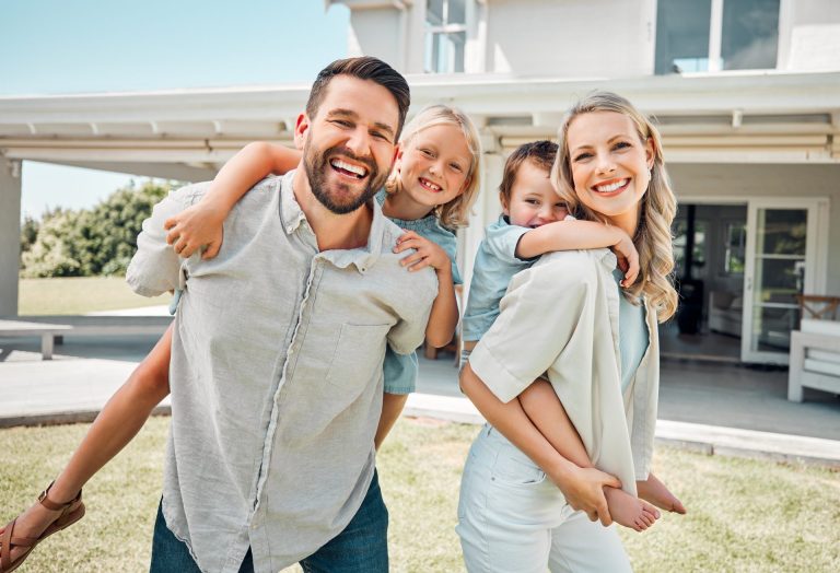 Happy family outside modern home carrying children