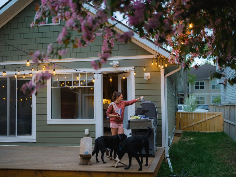 Woman grilling on backyard deck with dogs
