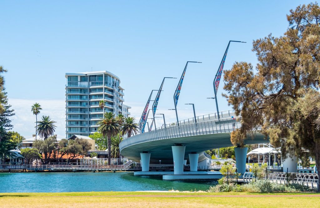 Modern bridge over river with apartments and palms