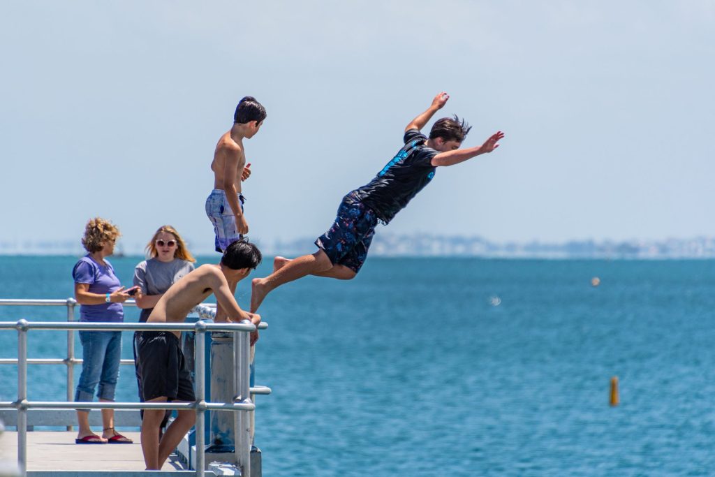 Teenager diving off pier into ocean