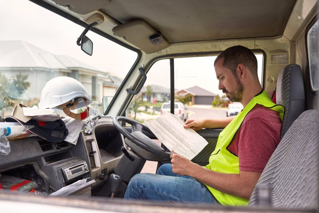 Construction worker reading plans inside work truck