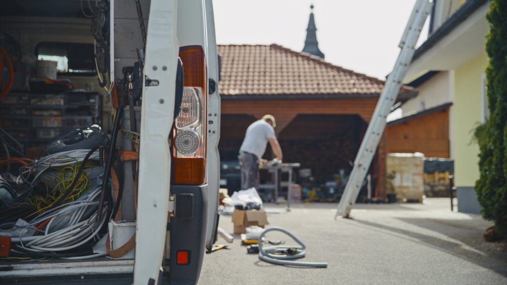 Tradesperson working beside van in suburban driveway
